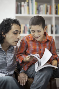 Father assisting son in doing homework at home