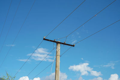 Low angle view of electricity pylon against blue sky