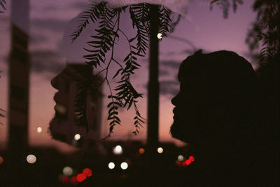Close-up portrait of silhouette man against illuminated plants