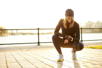 A backlit outdoor portrait of a woman checking her smart watch.