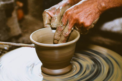 Cropped hand of person making pottery on wheel