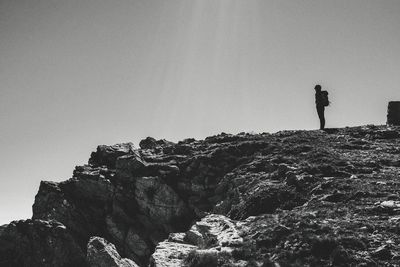 People standing on rock against clear sky