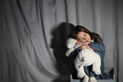 Young girl with teddy bear on bed at home