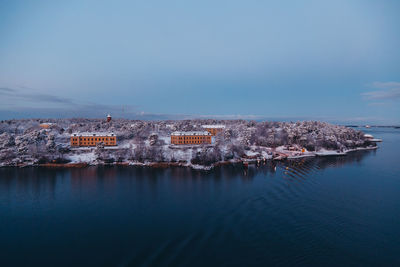 Aerial view of buildings by sea against clear sky