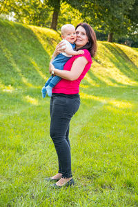 Full length of a smiling young woman standing on grass