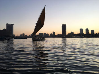 Scenic view of river by buildings against sky during sunset