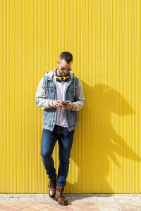 Portrait of a young cool man over yellow background.