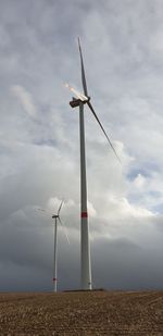 Wind turbines on field against sky