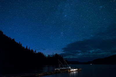 Boat moored by jetty in canim lake against sky at night