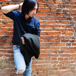 Fashionable young man posing against brick wall