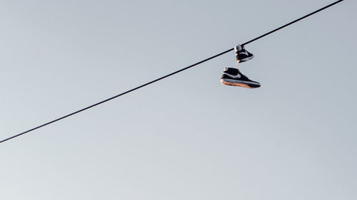 Low angle view of man hanging on rope against clear sky