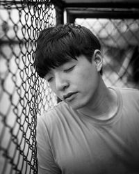 Close-up of man with closed eyes by chainlink fence