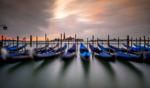 Blurred image of boats moored on wooden post at sunset