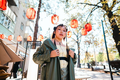 Portrait of young woman standing against building