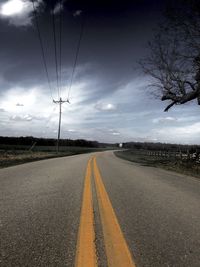 Road by electricity pylon against sky