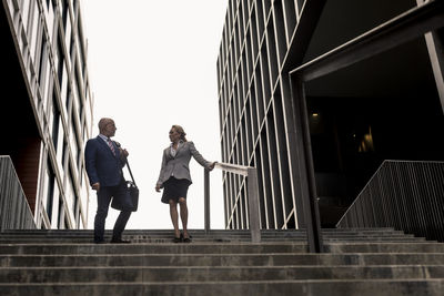 Senior businessman and businesswoman talking on stairs in the city