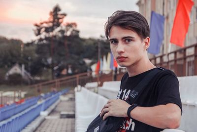 Portrait of young man sitting on chair at stadium