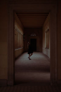 Full length of young woman standing in dark corridor