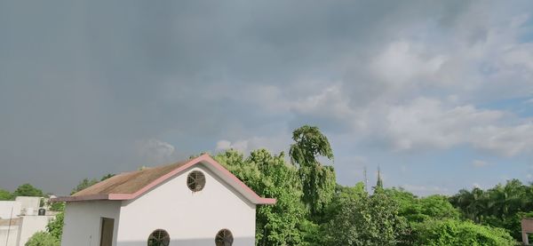 Low angle view of trees and building against sky