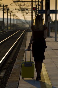 Rear view of silhouette woman walking at railroad station platform