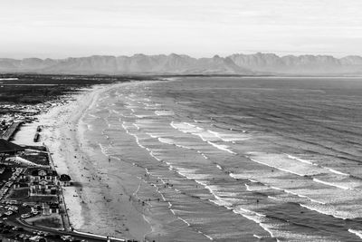 Scenic view of beach, waves rolling on and mountain in the distance 