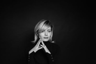 Portrait of young woman against black background
