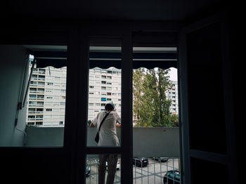 Rear view of man standing by window in building