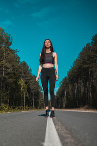 Full length portrait of woman on road against trees