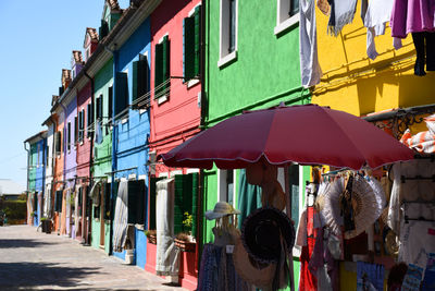 Multi colored umbrellas hanging on street amidst buildings in city