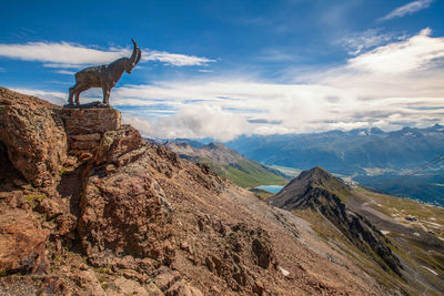 Side view of man standing on mountain against sky