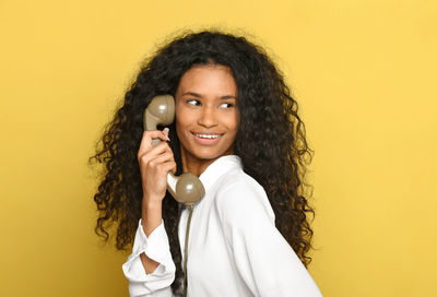 Portrait of a smiling young woman holding yellow camera