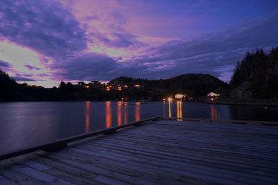 Pier over lake against sky at sunset