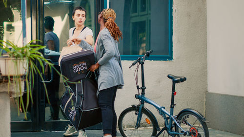 Side view of woman with bicycle against wall