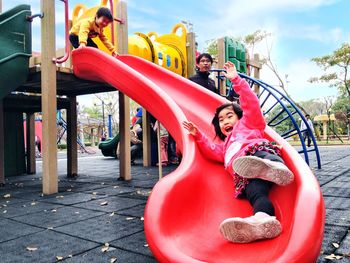 Rear view of women sitting on slide at playground