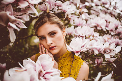 Portrait of young woman amidst pink flowers