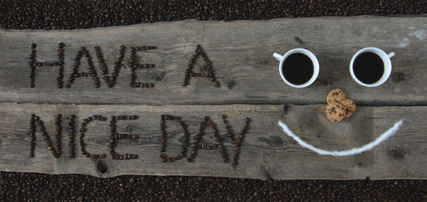 Directly above shot of anthropomorphic smiley face with message on plank