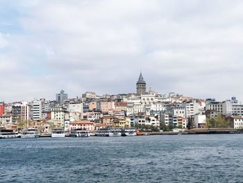 Sea by buildings against sky