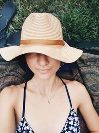 Directly above shot of woman wearing hat while lying on field