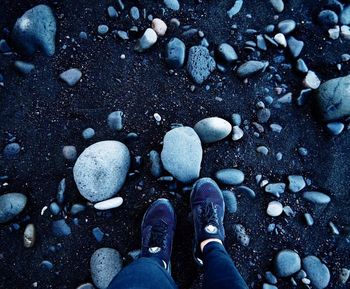 Low section of person standing on stones at beach