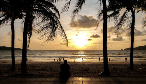 Silhouette people on beach against sky during sunset