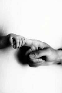 Close-up of hand holding hands over white background