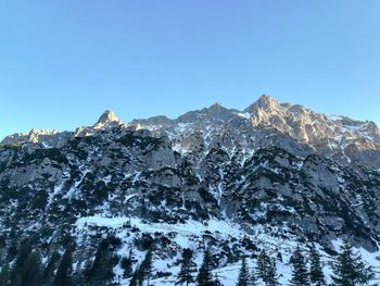 Low angle view of snowcapped mountains against clear blue sky