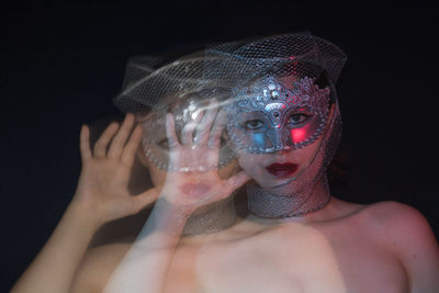 Blurred motion of shirtless woman wearing mask against black background