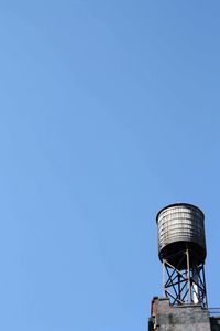 Low angle view of water tank against clear blue sky