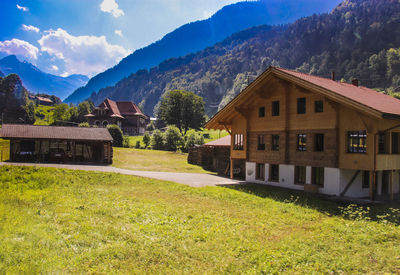 House on field by mountains against sky