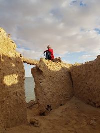 Low angle view of man sitting on rock