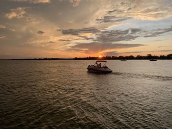 Boat sailing in sea against sky during sunset