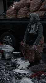 Woman wearing mask selling vegetables in market