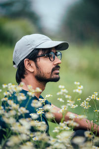 Side view of young man looking away while sitting on field