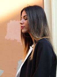 Portrait of young woman against wall